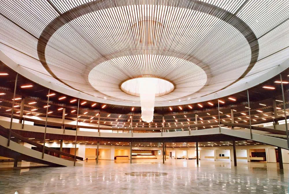 Inside the Palacio de Congresos Torremolinos — the circular main hall under a slatted-wood domed ceiling and a large central chandelier.